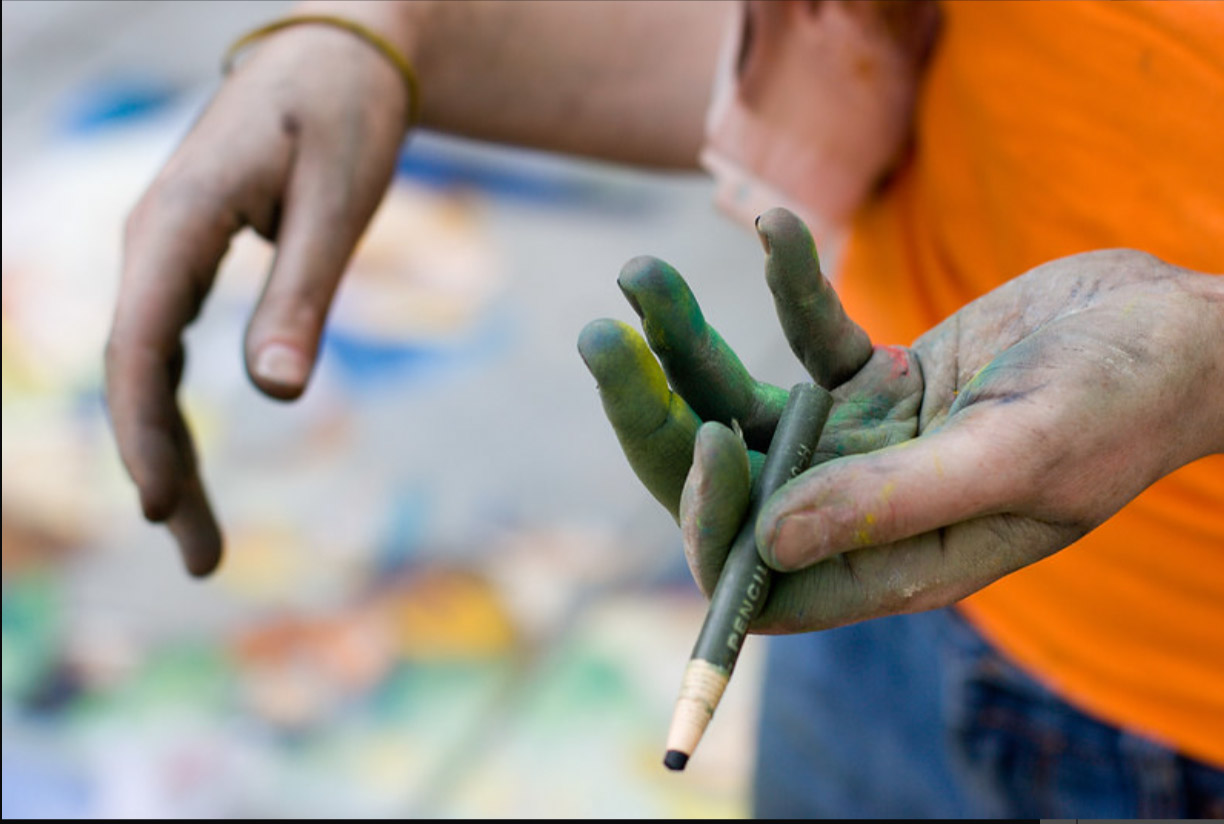 Dana Ellyn's chalk-stained hands holding pastel sticks while recreating Renoir's Luncheon of the Boating Party