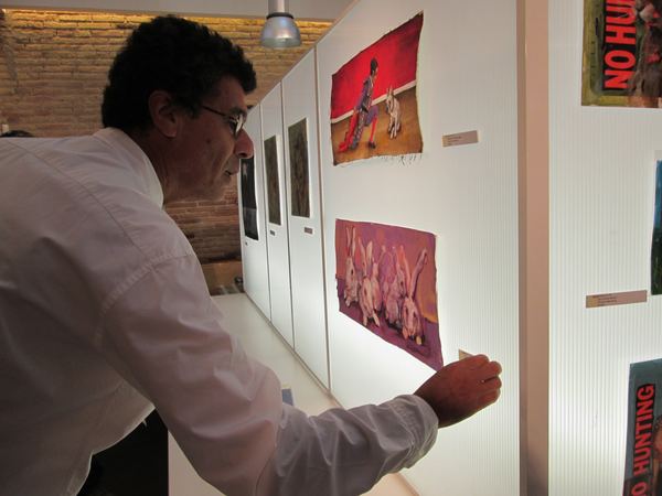 Gallery owner David Correa putting a red sold dot on a label beside Dana Ellyn's painting