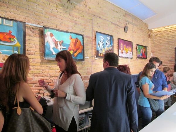 Visitors along the brick wall hung with Dana Ellyn's paintings