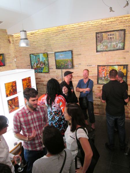 A crowd at the opening under Dana Ellyn's paintings on the brick wall