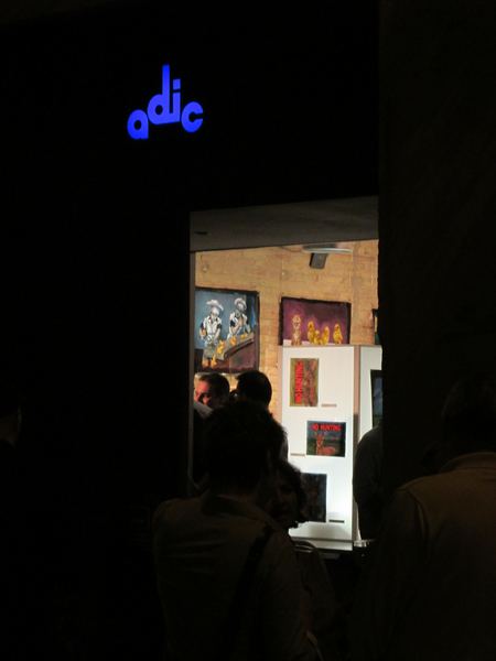 The gallery doorway at night, with Dana Ellyn's paintings visible inside