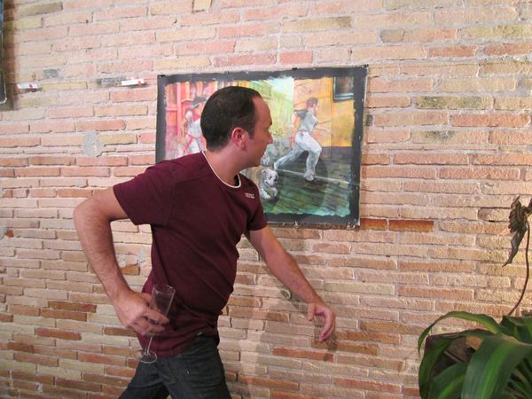 A visitor posing next to one of Dana Ellyn's paintings on the brick wall