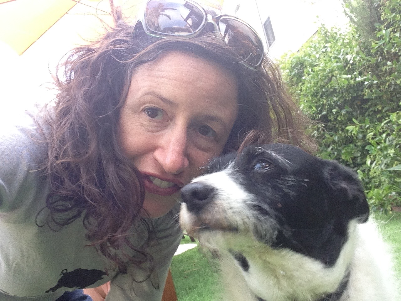 Dana Ellyn in a selfie with a black and white dog in a garden