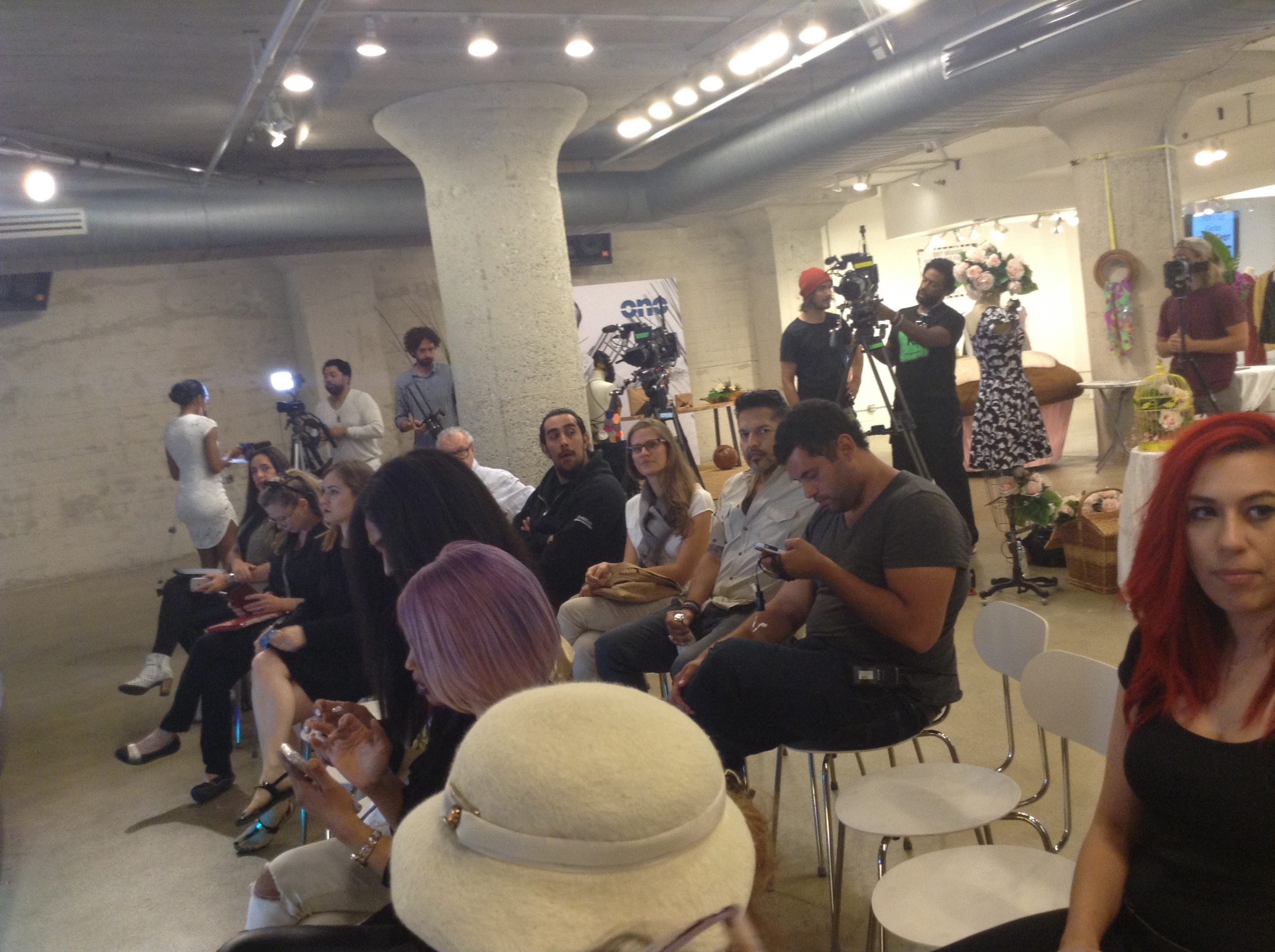 Seated audience at the Moda 360 runway with camera operators filming behind them