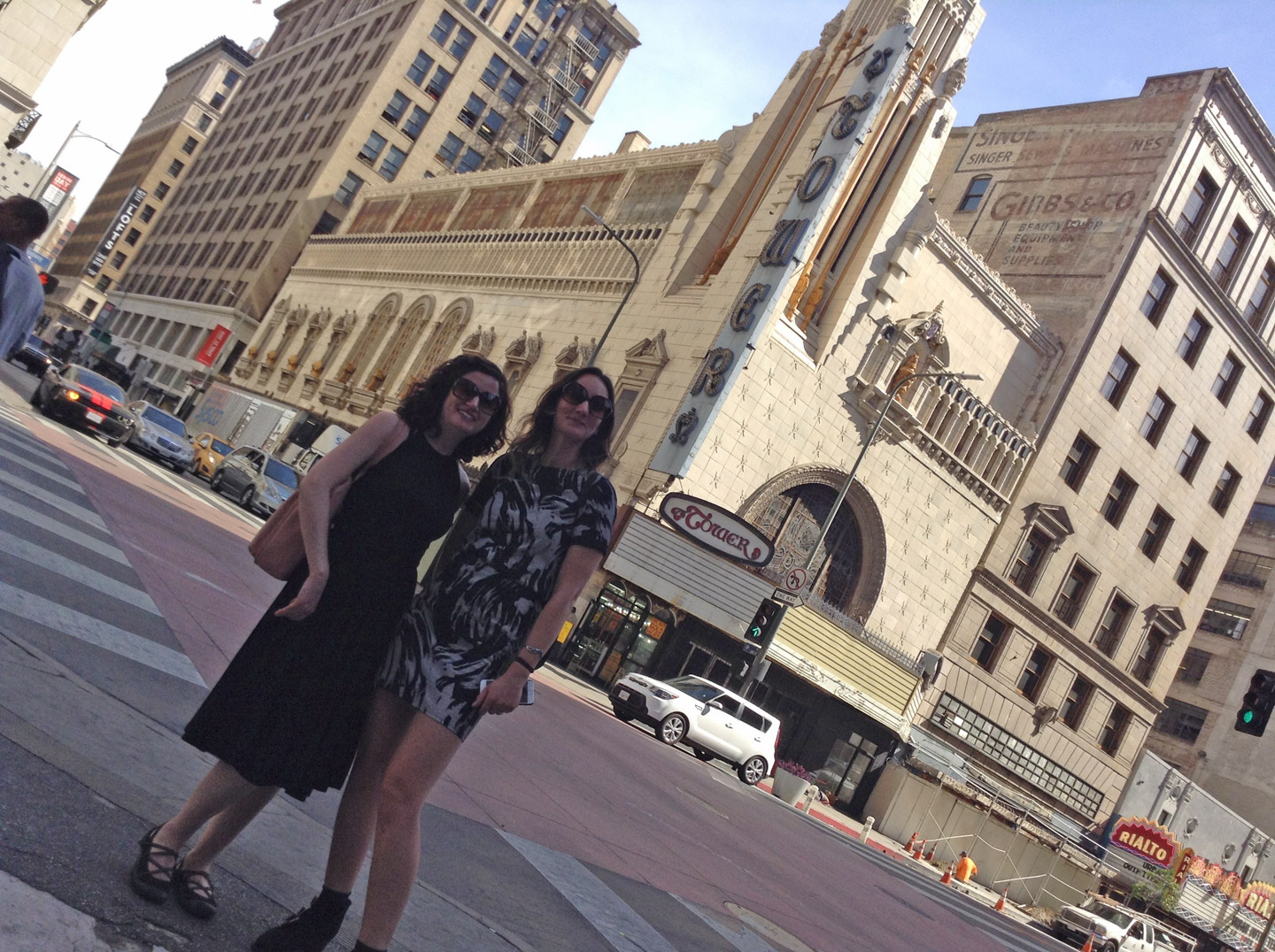 Dana Ellyn and designer Nancy Dee in sunglasses on a downtown Los Angeles street in front of the Tower Theatre