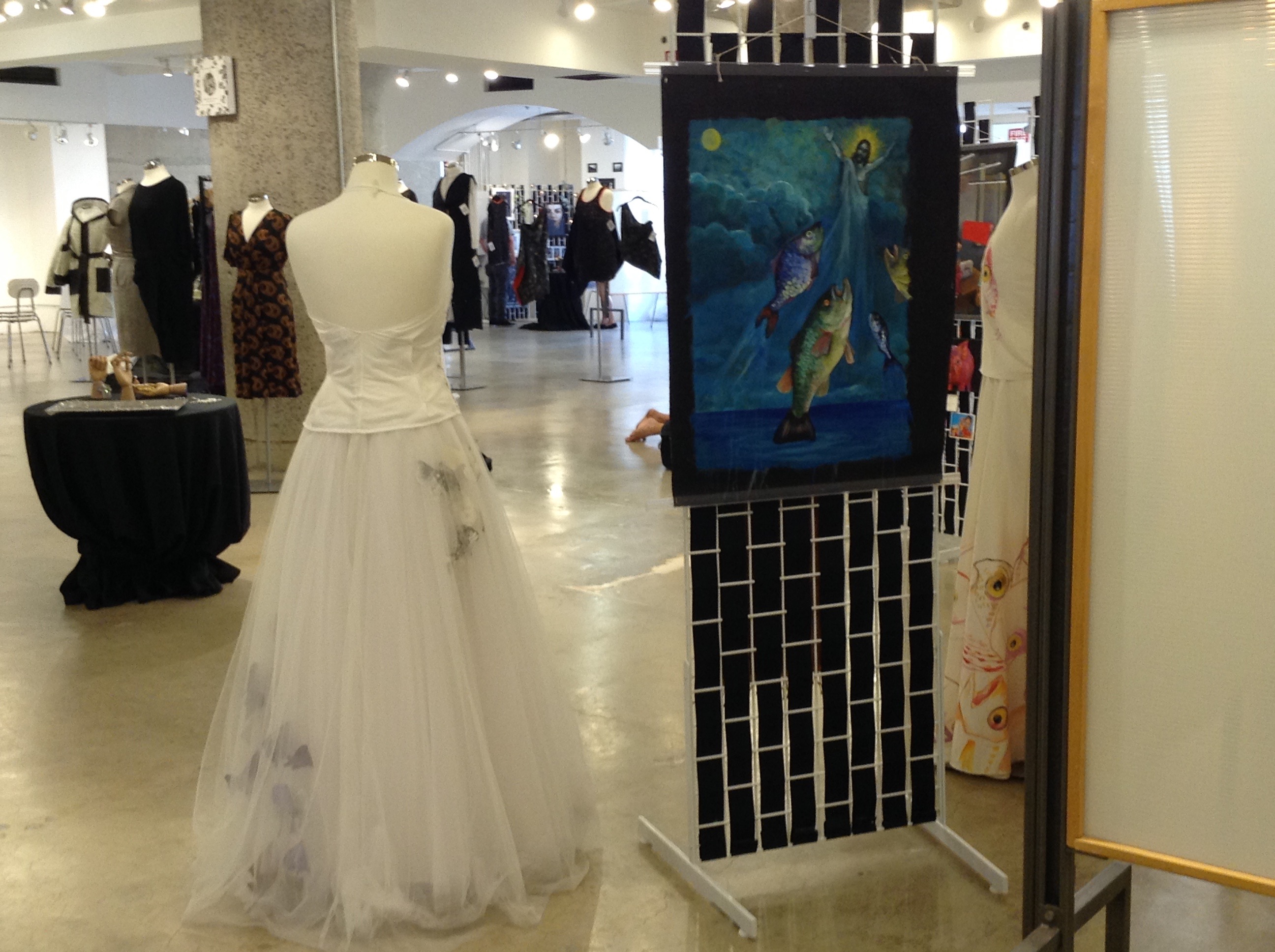 Tulle Bycatch, By Hand gown on a mannequin beside Fish Rapture, an oil painting by Dana Ellyn of fish rising toward a haloed figure