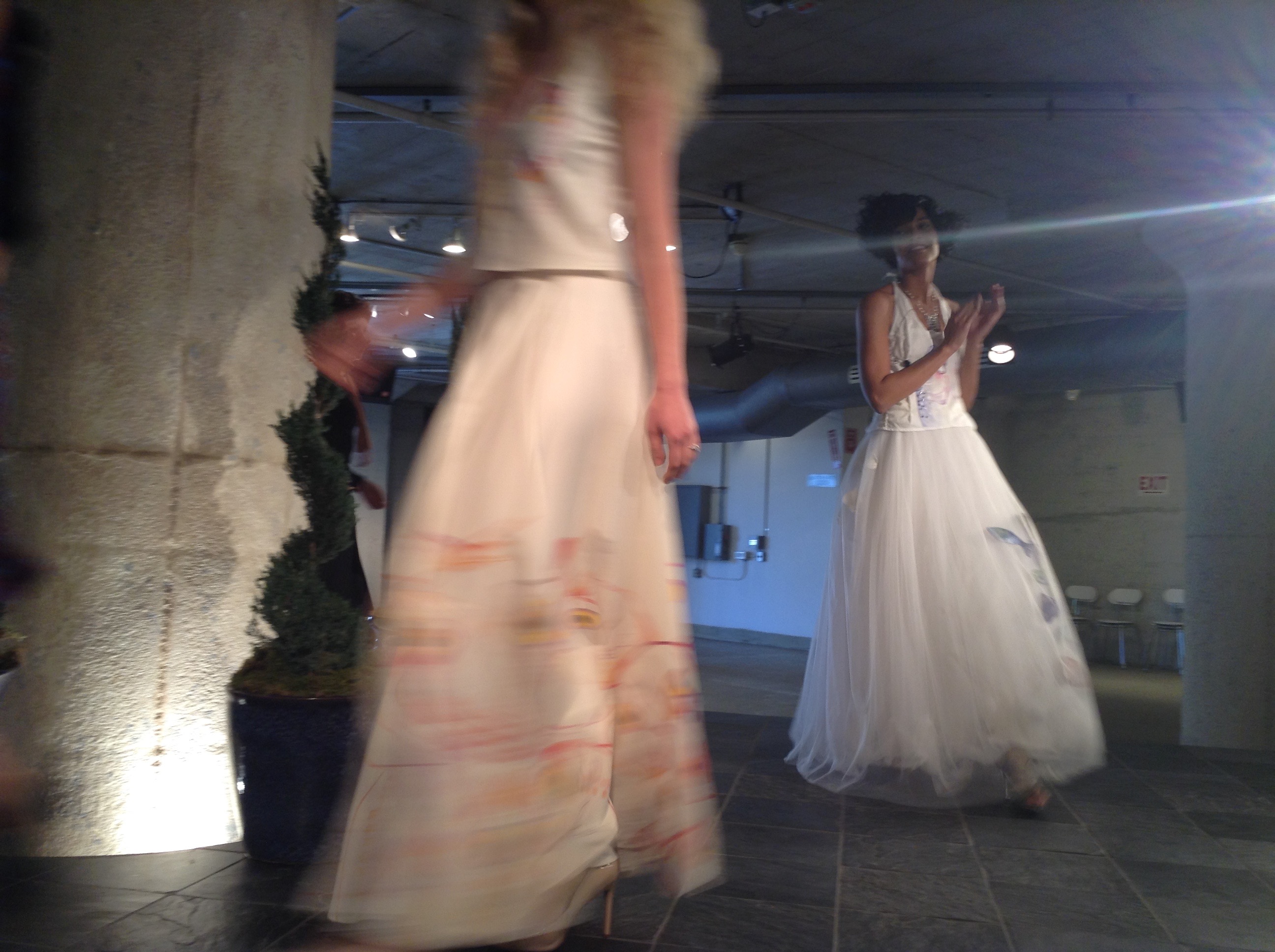 Two models on the Moda 360 runway in the Bycatch, By Hand dresses, the painted skirt in motion