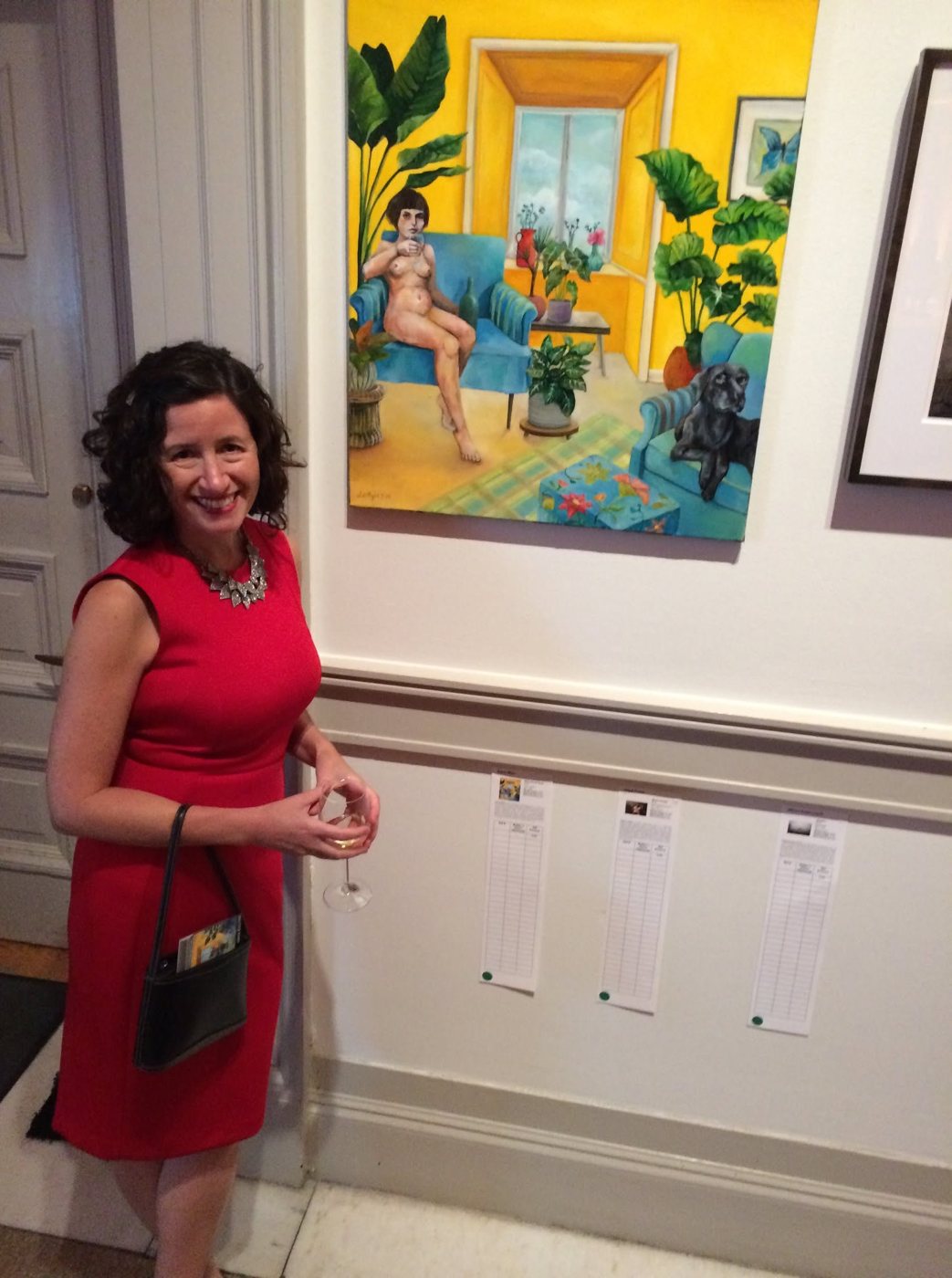 A woman in a red dress standing beside Dana Ellyn's painting Plant Based Nude at the 2019 Transformer auction