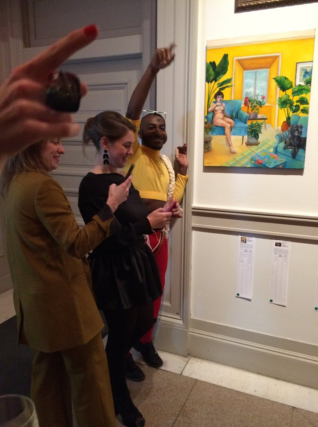 Guests crowding around and writing bids beside Dana Ellyn's painting Plant Based Nude at the 2019 Transformer auction